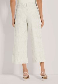 Lichtgroene wijde broek met textuur en bloemenborduursel. Heeft een hoge taille en een rafelige zoom. Gepaard met beige slingback hakken.