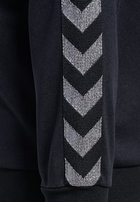 Czarna sportowa bluza z teksturowanym wzorem jodełki w kolorze srebrnym na rękawach, z prążkowanymi mankietami i gładkim wykończeniem.