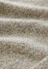 Textured fabric in beige and light gray tones, featuring a woven pattern with fine fibers, showing soft, gentle folds and a warm appearance.