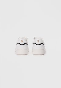 White leather sneakers with a wavy black design and pearl accent on the heel. Rubber sole with logo on the back. Smooth texture.