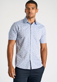 Camicetta azzurra a maniche corte con pois azzurri, colletto button-down e texture di cotone morbido. Presenta un design classico.