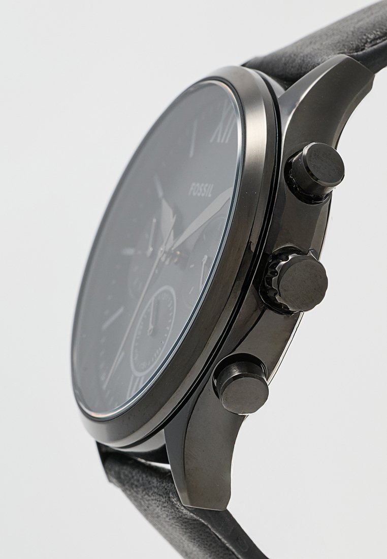 Reloj analógico negro con una esfera redonda y una caja de acero inoxidable negro. Presenta una correa de cuero, acentos plateados y tres subesferas.