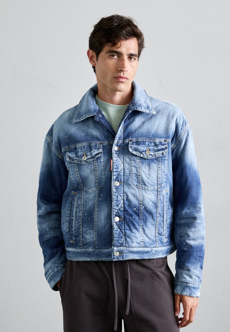 Light blue denim jacket with two chest pockets, silver buttons, and a slightly faded texture. Features a pointed collar and a relaxed fit.