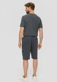 T-shirt gris mélangé à manches courtes avec col rond, associé à un short gris foncé jusqu'aux genoux avec poches latérales et texture douce.