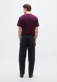 Vyno raudonumo medvilninis marškinėlis ir juodi džinsai iš džinsinio audinio. Marškinėliai turi apvalų kaklo iškirpimą; džinsai turi nugaros kišenes ir tiesias kojų siūles.