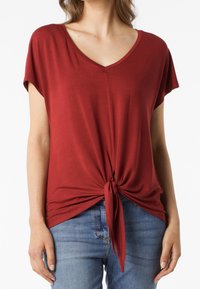T-shirt rossa con scollo a V e maniche corte, realizzata in tessuto morbido, con una vestibilità rilassata e una superficie testurizzata.
