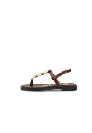 Sandalia plana marrón con adornos ovalados dorados en la tira y hebilla ajustable en el tobillo, mostrada de lado sobre fondo blanco.