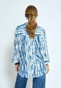 Camicia a maniche tre quarti in tessuto leggero, con motivo blu e bianco, dotata di yoke posteriore e vestibilità ampia.