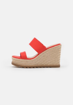 Sandale compensée avec deux brides rouges et un talon plateforme beige tressé, dotée d'une semelle marron rainurée pour une meilleure adhérence.