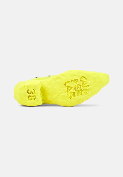 Klart gul sneakersula med texturerad yta, märkt med "38" och "BARA FÖR F." Har en konturerad form för stabilitet.