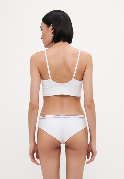 Witte bralette met verstelbare bandjes, gecombineerd met bijpassende slipjes met een logo-band in de taille, een gladde textuur en een minimalistisch ontwerp.