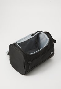 Bolsa de aseo rectangular negra con interior gris, desabrochada y abierta, mostrando el compartimento principal vacío y el bolsillo con cremallera lateral.