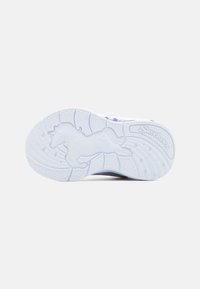 Valkoinen lenkkarin pohja, jossa on yksisarvinen kuvio, tekstuurilla varustetut urat pitoa varten ja "Skechers"-logo kohokuvioituna.