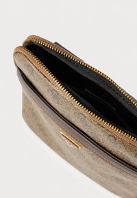 Brązowa i złota saszetka w wzór, zamykana na suwak. Wewnątrz wyłożona czarną tkaniną. Z przodu znajduje się złote logo z metalowymi elementami.