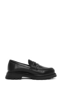 Mocassin en cuir noir avec une profile bas, des coutures texturées sur le devant et une semelle en caoutchouc épaisse. Il a un bout arrondi et un design à enfiler.