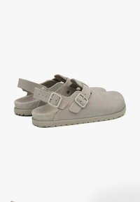 Lichtgrijze suède sandalen met verstelbare banden en gespaccenten. Rond toelopende neus en een geprofileerde zool voor grip. Lichtgewicht ontwerp.