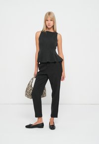 Sort, ærmeløs peplum top med et enkelt design, parret med skræddersyede sorte bukser. Accessories inkluderer en mønstret håndtaske og flade sko.