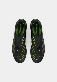 Black soccer shoes with dynamic yellow-green accents, sleek design, textured surface, and strategically placed striping patterns.