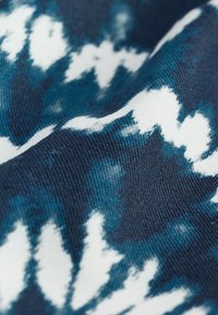 Kangas on tumel sinine ja valge lipsuvärviga muster, sileda tekstuuri ja pehme langevusega. Disainis on ebaühtlaseid kujundeid ja mustreid.