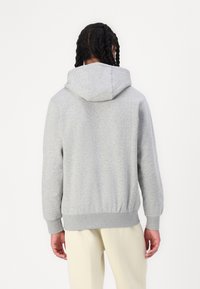 Sweatshirt cinzenta com textura suave, capuz ajustável com cordão, punhos e barra canelados. Apresenta um corte descontraído e design limpo.