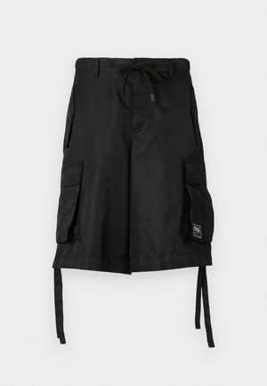 Pantalones cortos cargo negros que cuentan con una cintura ajustable con cordón, múltiples bolsillos laterales y correas de tela en el dobladillo para longitud ajustable. Textura suave.