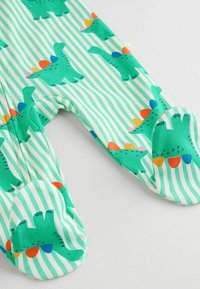 Grüner gestreifter Einteiler aus weichem Stoff, mit bunten Dinosaurierdrucken in Blau, Orange und Pink auf einem weißen Hintergrund.