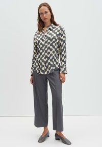 Long-sleeve shirt in cream with dark gray abstract pattern, paired with gray wide-leg trousers and gray flat shoes. Smooth fabric texture.