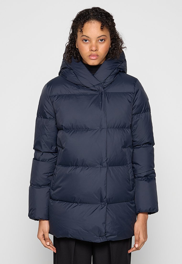 Granatowa kurtka puchowa z kapturem, o geometrycznym wzorze pikowania, z oversize'owymi rękawami i nieco dłuższym krojem dla dodatkowego ciepła.