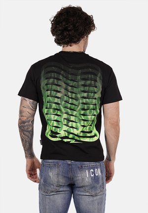 T-shirt nera a maniche corte con un motivo astratto verde sfumato sulla schiena, abbinata a jeans in denim grigi.