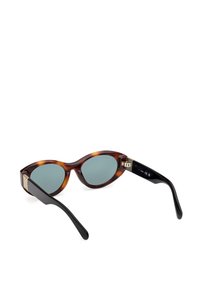 Gafas de sol de carey con lentes ovalados, cristal tintado verde y patillas negras. Un detalle de herrajes dorados en la patilla añade un toque decorativo.