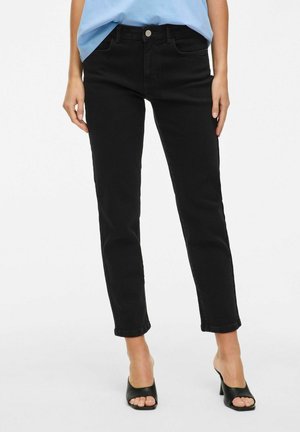 Zwarte denim jeans met een slim fit, vijf zakken en opgerolde boorden, gecombineerd met een lichtblauw shirt en zwarte open teen hakken.