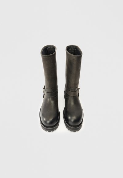 Botas de couro pretas com um acabamento suave, altura até a meio da panturrilha e sola plana. Apresenta uma tira com detalhe em metal no tornozelo.