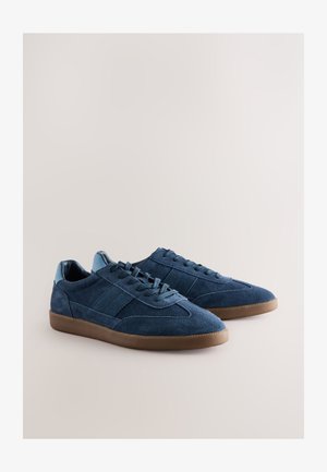 Tumesinised seemisnahast tossud ümarate ninade, samatoonsete paelte ja kummist tallaga. Kontsadel on sile nahast detail ning külgedel triibud.