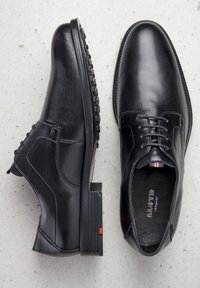 Chaussures habillées en cuir noir avec une texture lisse, bout rond, design à lacets, petit talon bloc et semelle en caoutchouc avec des détails de grip.