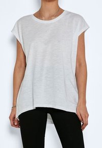 T-shirt bianco a maniche corte con vestibilità rilassata, scollo rotondo e orlo irregolare. Realizzato in tessuto leggero con un aspetto leggermente testurizzato.