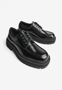 Scarpe in pelle nera con punta arrotondata, finitura liscia, design con lacci e suola in gomma zigrinata per una maggiore aderenza.