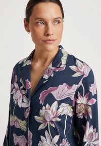Marineblauwe shirt met bloemmotief in roze en groen, voorzien van een gekartelde kraag en knoopsluiting, gemaakt van zachte stof.