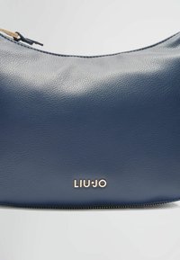 Granatowa skórzana torba o teksturowanej powierzchni, ze złotym logo „LIUJO”, zaokrąglonym kształtem i zamkiem błyskawicznym wzdłuż dolnej krawędzi.