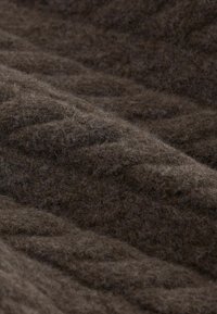 Țesătură texturată, de culoare maro închis, cu o suprafață moale și pufoasă. Prezintă un model ondulat, indicând un design țesut. Potrivită pentru îmbrăcăminte sau tapițerie.