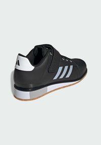 Black athletic shoe with textured upper, white accents, three gray stripes, reinforced heel, and rubber outsole with a gum-colored section.
