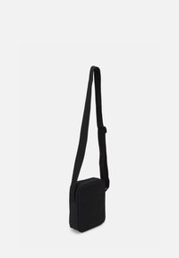 Borsa a tracolla nera di forma rettangolare, realizzata in tessuto liscio, dotata di una larga tracolla regolabile e senza hardware visibile.