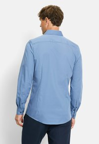 Light blue long-sleeve shirt with a classic collar, button cuffs, and a tailored fit. Smooth fabric with a slight sheen.
