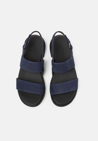 Marineblå ruskindsandaler med to brede stropper, slingback-design og en tekstureret sort gummisål. Minimalistisk stil med justerbart spænde.