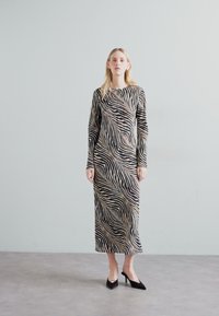 Ilga rankovė, prie kūno priglundanti suknelė su juodai-beige dryžuotu zebro raštu. Minkšta medžiaga, su apvaliais iškirpimu ir iki blauzdų ilgio.