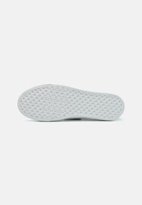 Semelle en caoutchouc blanc avec un motif géométrique de losanges entrelacés, présentant une surface texturée pour une meilleure adhérence.