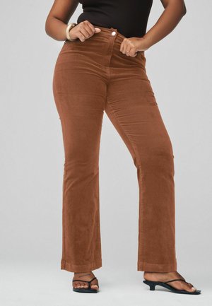 Bruna corduroy byxor med utsvängda ben, hög midja, framknäppning och slät yta. Matchas med svarta sandaler.