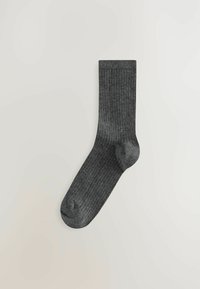 Grå ribbad strumpa tillverkad av ett mjukt material. Har förstärkt tå och häl. Designen är enkel med vertikal textur genom hela strumpan.