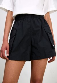 Black shorts made of lightweight material. Features an elastic waistband, side pockets, and a small logo on the right hem. Flat texture.