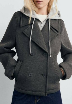 Giacca doppiopetto grigio scuro realizzata in materiale testurizzato, con cappuccio e zip argentata, dotata di grandi bottoni neri e tasche laterali.
