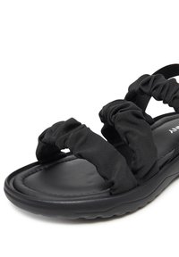 Czarne sandały z miękkimi paskami z tkaniny z marszczeniami, miękką wyściółką i gładkim, zaokrąglonym kształtem.